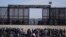 FILE - Migrants who crossed the border from Mexico into the US wait next to the US border wall where US Border Patrol agents stand guard, seen from Ciudad Juarez, Mexico, March 30, 2023. 