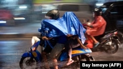 Pengendara motor mengenakan jas hujan saat berkendara saat hujan deras mengguyur Ibu Kota Jakarta pada 19 Januari 2022. (Foto: BAY ISMOYO/AFP)