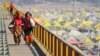 Devotees carry their belongings as they walk over a bridge during the annual religious Hindu festival of Magh Mela on the banks of Sangam in Prayagraj on Feb. 5, 2023. In 2018, Prayagraj's name was changed from Allahabad. 