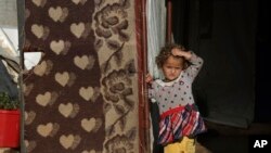 FILE - A displaced Syrian child in an encampment in northwestern Syrian stands outside a tent in the village of Harbnoush, May 13, 2024.