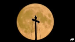 The August super blue moon sets behind the St. Basil's Cathedral in Red Square in Moscow, Russia, Aug. 30, 2023. 