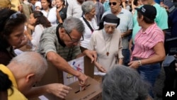 A voter casts his ballot at a polling station during opposition primary presidential election at Luis Brion square in Caracas, Venezuela, Oct. 22, 2023. 