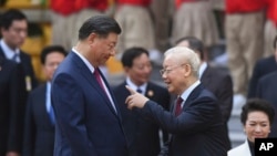 China's President Xi Jinping, center left, and Vietnam's Communist Party General Secretary Nguyen Phu Trong, center right, attend a welcome ceremony at the Presidential Palace in Hanoi, Vietnam, Tuesday Dec. 12, 2023. (Nhac Nguyen/Pool via AP) 