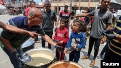 Sejumlah warga Palestina berkumpul untuk mendapatkan makanan yang dimasak oleh pekerja World Central Kitchen (WCK) di Deir Al-Balah, Jalur Gaza, pada 1 Mei 2024. (Foto: Reuters/Ramadan Abed)