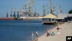 FILE - Local residents relax on a city beach in Berdiansk, a region under Russian military control, southeastern Ukraine, June 14, 2022. (AP Photo)
