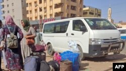 Watu wakiwa na mizigo yao wakisubiri kwenye kituo cha basi kilichopo kusini mwa Khartoum, tarehe 8 Mei 2023. Picha na AFP. 
