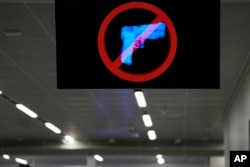 A television displays a "no guns" sign at the Transportation Security Administration security area at the Hartsfield-Jackson Atlanta International Airport on Wednesday, Jan. 25, 2023, in Atlanta. (AP Photo/Brynn Anderson)