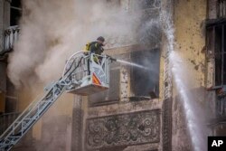A firefighter sprays water inside a building at the site of a Russian attack, in Kyiv, Ukraine, March 21, 2024. More than two dozen missiles were shot down over Kyiv on Thursday morning, said Serhii Popko, head of the Kyiv City Military Administration.