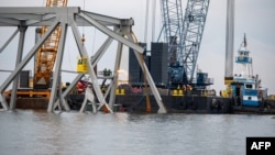 Para kru pembongkaran memotong bagian atas sisi utara Jembatan Francis Scott Key yang runtuh menjadi beberapa bagian yang lebih kecil untuk dipindahkan secara aman dengan derek di Sungai Patapsco, 30 Maret 2024.