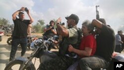 2023年10月7日，一名被俘的以色列平民（中，穿红衣的女士）被从卡法阿扎基布兹运送到加沙地带。(AP Photo/Hatem Ali)