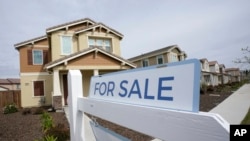 FILE - A "for sale" sign is posted in front of a home in Sacramento, California, March 3, 2022.