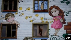 A woman takes broken glass from an apartment building window after a Russian attack in Kyiv, Ukraine, Jan. 23, 2024. Some journalists' motivation to work in Ukraine comes from a sense that too few people with personal ties to the nation were doing so.