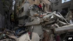 Palestinians inspect the rubble of a destroyed building that the Israeli military said targeted the house of an Islamic Jihad member in Gaza City, May 13, 2023.