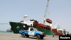 A coastguard soldier stands on a patrol vehicle while a commercial ship unloads containers in the Houthi-held Red Sea port of Hodeidah, Yemen, Feb. 25, 2023. 