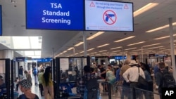 FILE - A sign warns travelers not to bring guns through the Transportation Security Administration checkpoint at Orlando International Airport in Orlando, Florida, April 23, 2022.