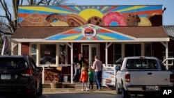 A customer holds the door for a family arriving at Leavitt's Country Bakery, Thursday, April 13, 2023, in Conway, N.H. (AP Photo/Robert F. Bukaty)