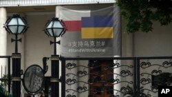 A paramilitary policeman stands watch at the Polish Embassy, which displays a banner showing support for Ukraine, in Beijing, May 17, 2023. 