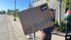 Pro-Palestinian supporters demanding divestment from companies that profit off the Israel-Hamas war hold signs outside as University of Minnesota regents meet, May 10, 2024, in Minneapolis.