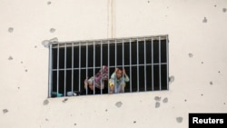 Displaced Palestinians who fled their houses due to Israeli strikes look out from a window as they take shelter, in Khan Younis in the southern Gaza Strip, July 24, 2024.