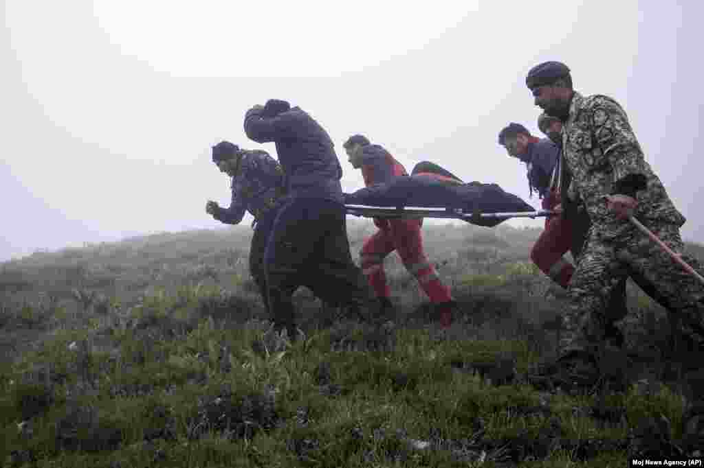 In this photo provided by Moj News Agency, rescue teams members carry body of a victim after a helicopter carrying Iranian President Ebrahim Raisi crashed in Varzaghan, northwestern Iran, May 20, 2024. 