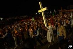 A youngster carries a cross during a Rosary and Candle procession at the Our Lady of Fatima shrine, in Fatima, Portugal, Aug. 4, 2023. Pope Francis is in Portugal through the weekend to preside over World Youth Day, a six-day jamboree.