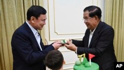 នាយករដ្ឋមន្ត្រីកម្ពុជា លោក ហ៊ុន សែន ជូននំមួយចានដល់អតីតនាយករដ្ឋមន្ត្រីថៃ លោក Thanksin Shinawatra ក្នុងជំនួបមួយនៅគេហដ្ឋានរបស់លោក ហ៊ុន សែន នៅទីក្រុងតាខ្មៅ ខេត្តកណ្តាល កាលពីថ្ងៃទី ៥ ខែសីហា ឆ្នាំ ២០២៣។ (Cambodia's Prime Minister Telegram via AP)