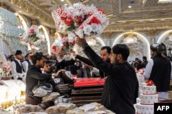Volunteers distribute flower bouquets to the grooms during a mass wedding ceremony at a wedding hall in Kabul, Afghanistan, Dec. 25, 2023.