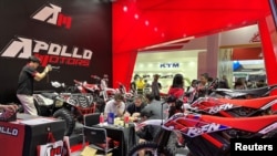 2023年4月15日在广州举行的“广交会”上，参观者在询问Apollo Motors展出的摩托车等产品。