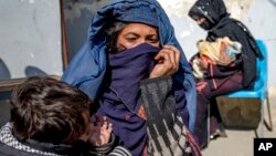 FILE - Mothers with malnourished babies wait for help at a World Food Program clinic in Kabul, Afghanistan, Jan. 26, 2023.