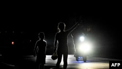 A woman with her son signals a car on a dark street during a blackout in Bauta municipality, Artemisa province, Cuba, on March 18, 2024. 