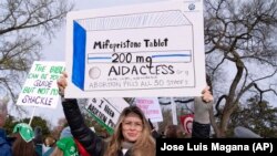 FILE - Abortion-rights activists holds a signs in protest outside of the Supreme Court, March 26, 2024, in Washington. Louisiana lawmakers have approved a bill that would classify two abortion-inducing drugs as a controlled and dangerous substance.