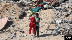 খান ইউনিসে ইসরায়েলি বোমা হামলায় বিধ্বস্ত একটি ভবনের ধ্বংসস্তূপ থেকে পাওয়া খেলনা ভালুকসহ একটি ফিলিস্তিনি শিশুকে দেখা যাচ্ছে। ২১ জুন, ২০২৪।