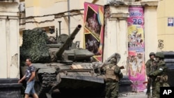 Russian servicemen guard an area standing in front of a tank in a street in Rostov-on-Don, Russia, June 24, 2023. 