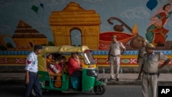 FILE - Policemen stop an auto rickshaw at a checkpoint as traffic restrictions and diversions are placed ahead of the weekend's G20 Summit, in New Delhi, Sept. 8, 2023.
