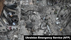 Foto udara menunjukkan petugas penyelamat bekerja di lokasi serangan rudal di ibu kota Kyiv, Ukraina. Lima orang termasuk seorang gadis remaja terluka dalam serangan rudal Rusia hari Senin (25/3). (AFP)