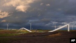 The remains of a tornado-damaged wind turbine touch the ground in a field, near Prescott, Iowa, May 21, 2024.