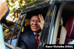 រូបឯកសារ៖ លោក កឹម សុខា អតីតមេដឹកនាំគណបក្សសង្គ្រោះជាតិ លើកដៃស្វាគមន៍ក្រុមអ្នកសារព័ត៌មាន ខណៈលោកចាកចេញពីគេហដ្ឋានរបស់លោក មុនសេចក្តីប្រកាសសាលក្រមកាត់ក្តីរូបលោកពីបទក្បត់ជាតិ នៅរាជធានីភ្នំពេញ ថ្ងៃទី ៣ ខែមីនា ឆ្នាំ ២០២៣។ (កាន់ វិច្ឆិកា/វីអូអេ)