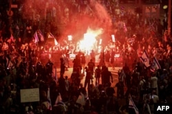 Relatives and supporters of hostages taken captive by Palestinian militants in Gaza during the Oct. 7 attacks, light flares and wave national flags during a demonstration calling for their release, in the Israeli city of Tel Aviv on April 27, 2024.