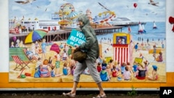 Žena prolazi pored plakata Reformske stranke Najdžela Faraža u Klektonu na moru (Foto: AP/Vadim Ghirda)