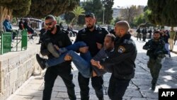 Polisi Israel menahan seorang pria Palestina di Masjid Al-Aqsa menyusul bentrokan yang terjadi lokasi tersebut pada 5 April 2023. (Foto: AFP/Ahmad Gharabli)