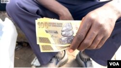 FILE - A street vendor holding Zimbabwe's outgoing currency in Harare in April 2024. (Columbus Mavhunga/VOA)
