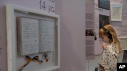 A child listens to audio with a video at the War Diaries exhibition, showcasing the personal diaries of Ukrainian children who have witnessed the war, hosted by the Amsterdam city hall, Netherlands, Aug. 17, 2023.
