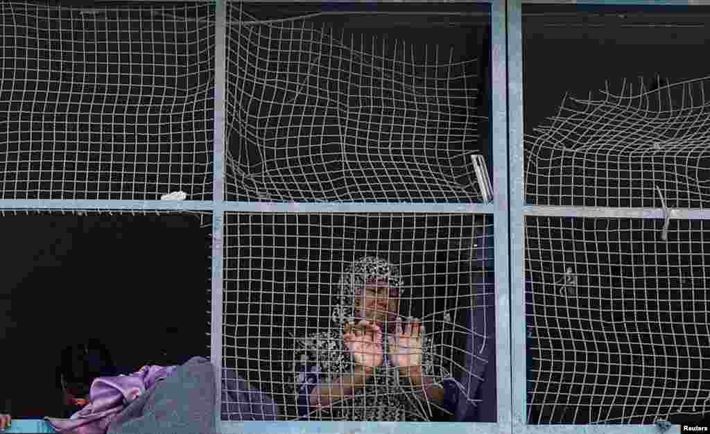 A Palestinian woman looks through the damaged windows of a classroom in a UNRWA school, after an air strike on a house neighboring the school in Khan Younis, in the southern Gaza Strip.