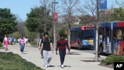 រូបឯកសារ៖ សិស្ស​ដើរ​តាម​មហាវិថី Jayhawk ជា​ផ្លូវ​ធំ​កាត់​តាម​បរិវេណ​សាកលវិទ្យាល័យ Kansas ក្នុង​ទីក្រុង Lawrence រដ្ឋ Kansas ថ្ងៃ​ទី ១២ ខែ​មេសា ឆ្នាំ ២០២៤។