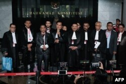 Tim kuasa hukum Menteri Pertahanan Prabowo Subianto berbicara kepada media usai sidang pertama permohonan calon penantang pemilu presiden Anies Baswedan terkait pemilu Februari 2024, di Mahkamah Konstitusi di Jakarta, 27 Maret 2024. (Yasuyoshi CHIBA / AFP)