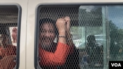 លោក ថាច់ សេដ្ឋា អនុប្រធានគណបក្សភ្លើងទៀន បង្ហាញខ្នោះដៃពីក្នុងឡាន នៅពេលលោកត្រូវបានដឹកចេញពីតុលាការកំពូលទៅពន្ធនាគារព្រៃស កាលពីថ្ងៃទី១៩ ខែមិថុនា ឆ្នាំ២០២៣។ (លាស់ លីបលីប/វីអូអេ)