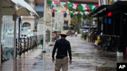 A tourist walks along the harbor with shops and restaurants closed by the arrival of Hurricane Norma in Cabo San Lucas, Mexico, Oct. 20, 2023.