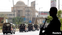 FILE - Siluet seorang polisi saat berjaga sementara pasukan paramiliter berpatroli sebagai tindakan pengamanan, menyusul kunjungan Presiden Iran Ebrahim Raisi, di Karachi, 23 April 2024.