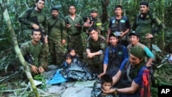 In this photo released by Colombia's Armed Forces Press Office, soldiers and Indigenous men pose for a photo with the four Indigenous brothers who were missing after a deadly plane crash, in the Solano jungle, Caqueta state, Colombia, June 9, 2023. 