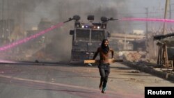 A supporter of Kenya's opposition leader Raila Odinga runs in front of a water canon during a nationwide protest over cost of living and President William Ruto's government in Nairobi, Kenya, March 30, 2023